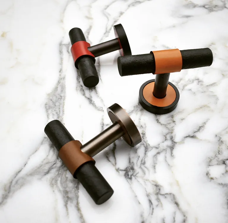 Design Door Handles by House of Eroju in black with leather details in brown, red and orange shown on a marble surface