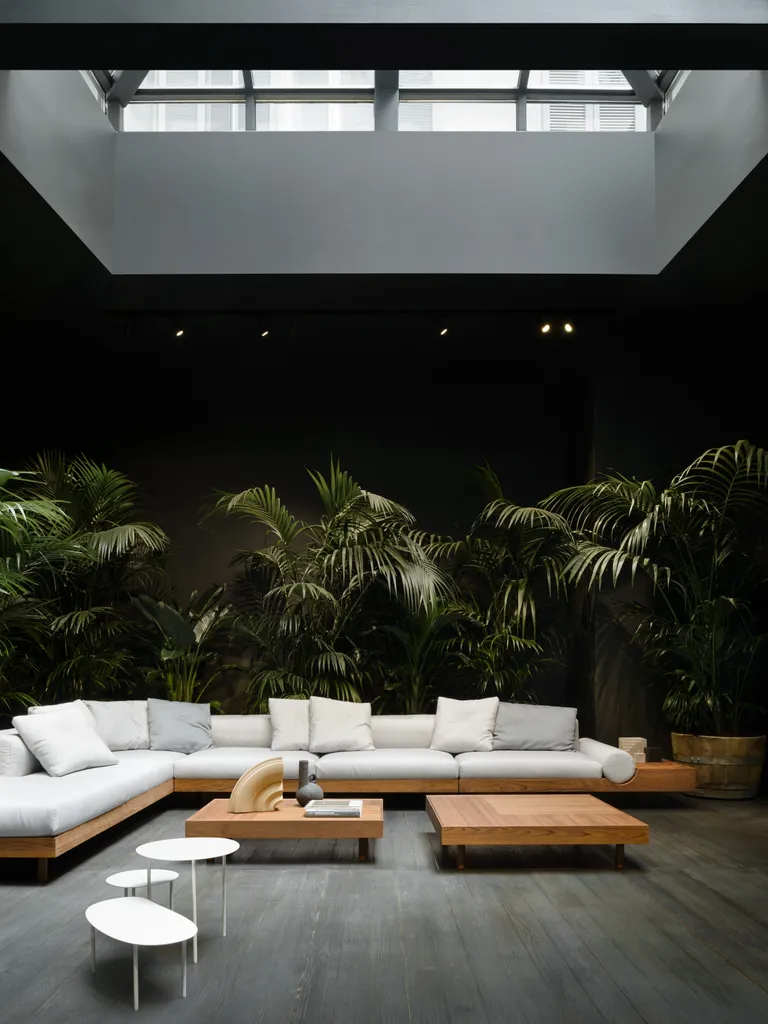 Interior of Living Divani Gallery with dark surfaces and plants framing a white sofa